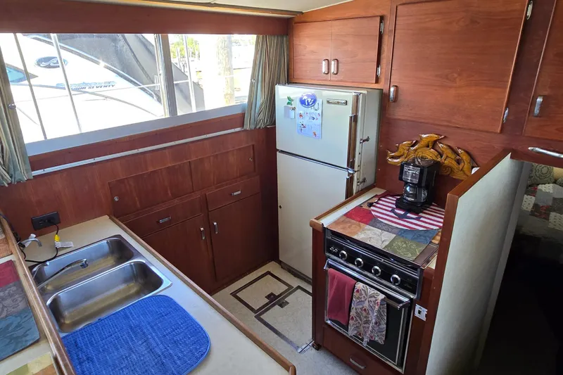 Slide: The Image of 1979 Chris-Craft 410 Motor Yacht kitchen with wood cabinets, stove, and refrigerator. - 13