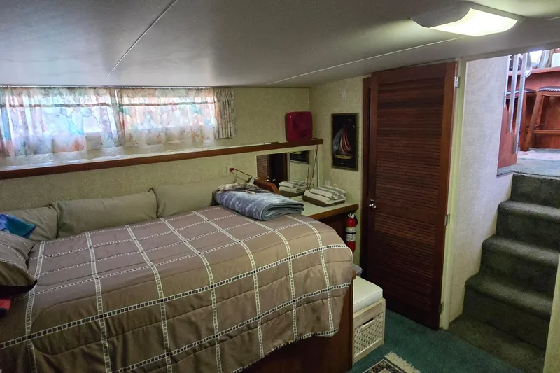 Slide: The Image of 1979 Chris-Craft 410 Motor Yacht interior cabin with bed, stairs, and wooden door. - 25