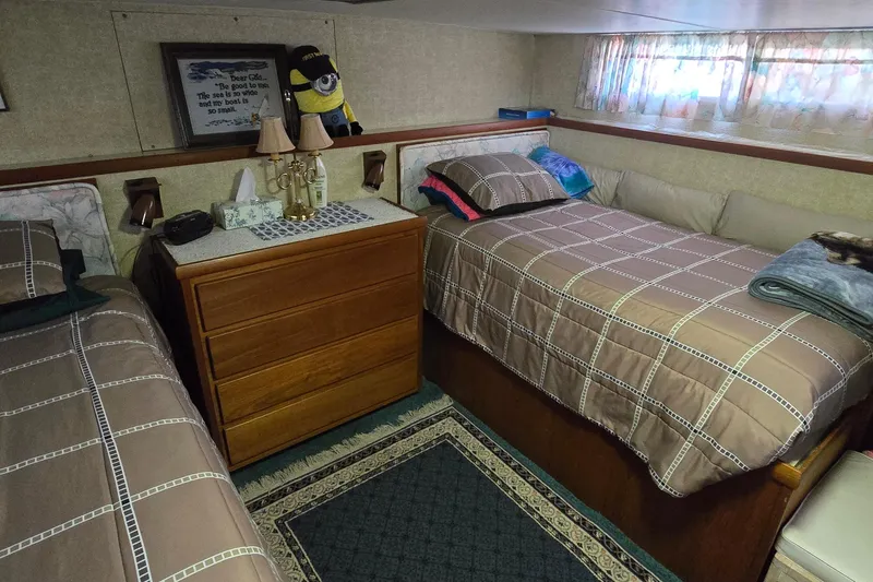 Slide: The Image of Cozy cabin interior of 1979 Chris-Craft 410 Motor Yacht with twin beds and wooden dresser. - 28