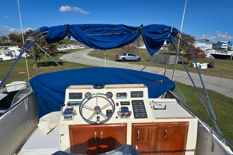 Slide: The Image of 1979 Chris-Craft 410 Motor Yacht helm with blue canopy, parked on grassy area. - 9