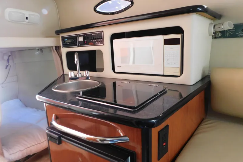 Slide: The Image of 2001 Chaparral Signature 240 boat interior with kitchenette, featuring sink, stove, and microwave. - 26