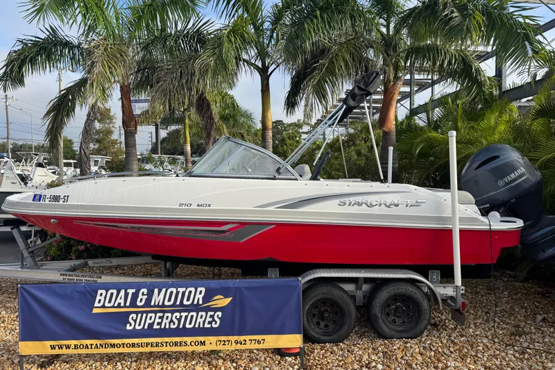 The Image of 2019 Starcraft MDX 210 OB boat on trailer at dealership, surrounded by palm trees. - 1