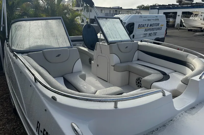 Slide: The Image of 2019 Starcraft MDX 210 OB boat with sleek seating and windshield, parked at a dealership. - 6