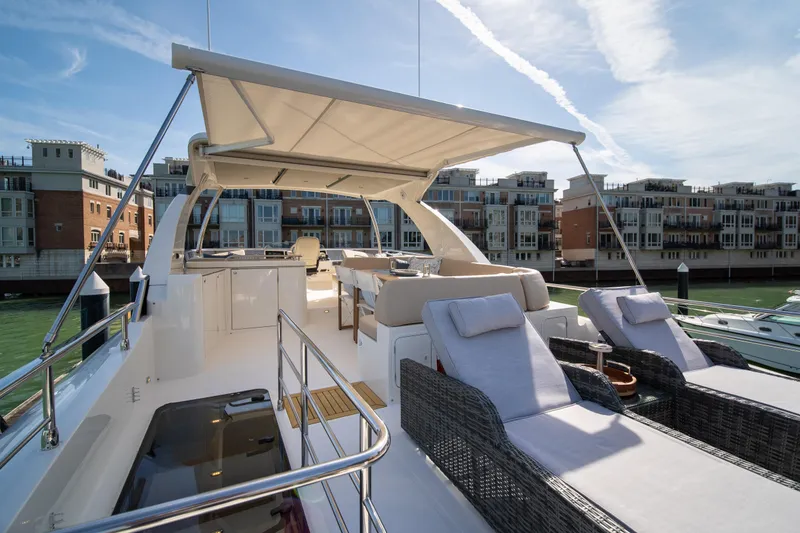 Slide: The Image of Luxurious 2018 Absolute 58 Navetta yacht with sun loungers and canopy, docked near waterfront buildings. - 29