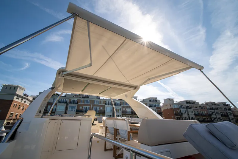 Slide: The Image of Luxurious 2018 Absolute 58 Navetta yacht with sunshade, docked near modern buildings. - 30