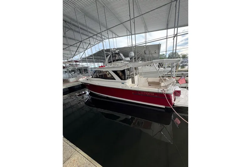 The Image of 2020 Cutwater C-30S boat docked under a metal canopy, featuring a red hull. - 0