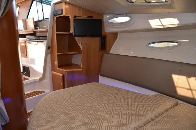 Slide: The Image of 2020 Cutwater C-30S interior cabin with bed, shelves, and porthole windows. - 19