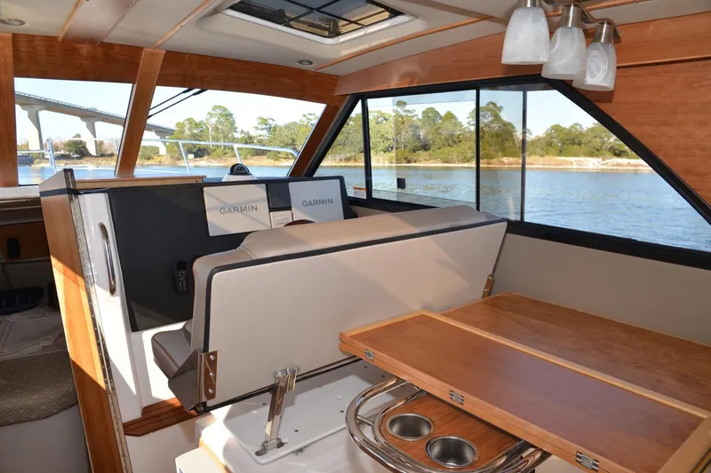 Slide: The Image of 2020 Cutwater C-30S interior with Garmin navigation, wooden table, and scenic water view. - 9