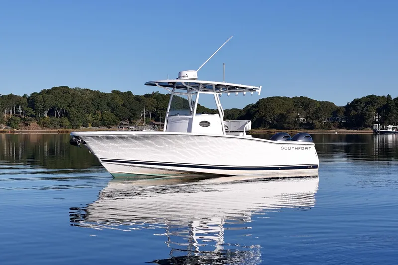 Slide: The Image of 2019 Southport 272 TE boat on calm water with forested shoreline background. - 2
