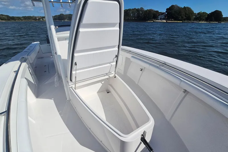 Slide: The Image of 2019 Southport 272 TE boat with open storage compartment on deck, near scenic shoreline. - 41