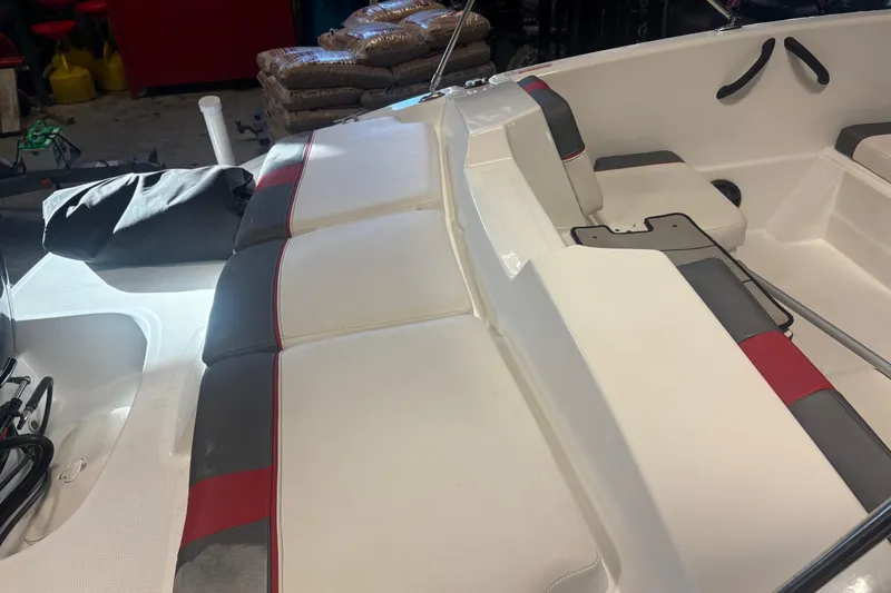 Slide: The Image of 2020 Tahoe T16 boat interior with white and red seating in a garage setting. - 13