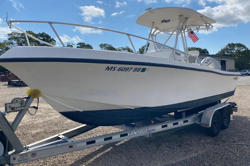 Slide: The Image of 2002 Mako 221 Center Console boat docked in a marina under clear blue skies. - 2