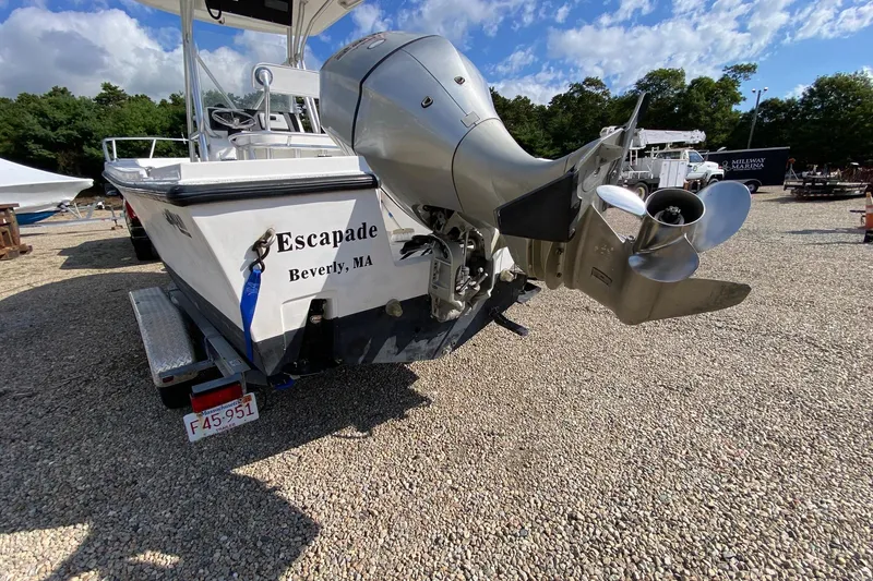 Slide: The Image of 2002 Mako 221 Center Console boat with outboard motor, named "Escapade," on gravel lot. - 5