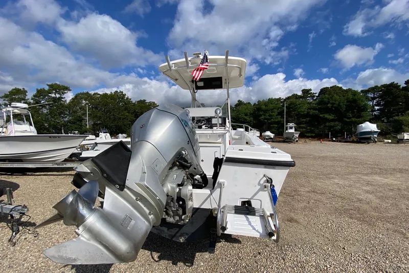 Slide: The Image of 2002 Mako 221 Center Console boat with outboard motor, parked on gravel lot under blue sky. - 6