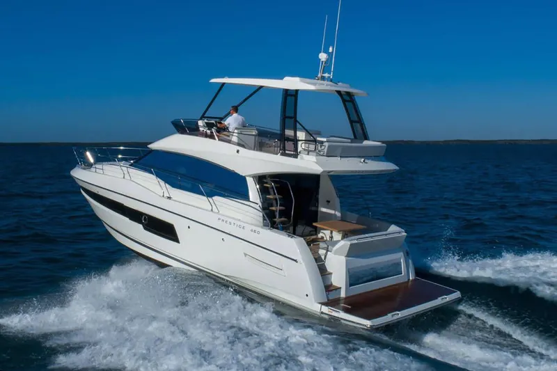 Slide: The Image of 2024 Prestige 460 yacht cruising near rocky cliffs on a sunny day. - 2