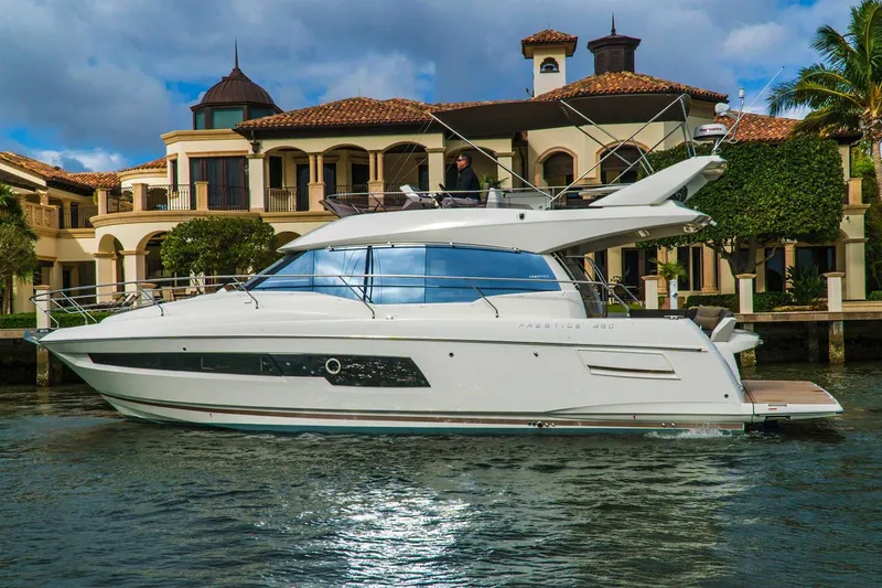 Slide: The Image of 2024 Prestige 460 yacht, sleek design, docked by rocky shoreline. - 7