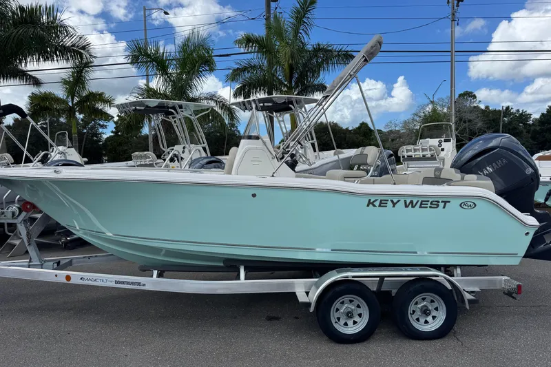 The Image of 2026 Key West 203 FS boat on trailer, palm trees in background, clear sky. - 1
