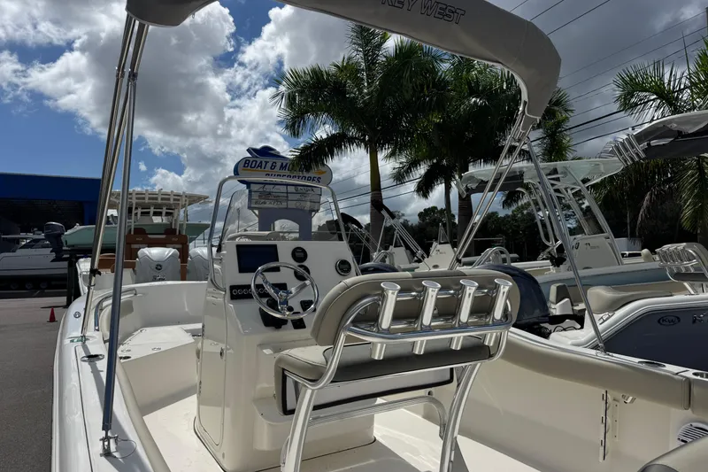 Slide: The Image of 2026 Key West 203 FS boat interior with steering console, palm trees, and cloudy sky. - 8