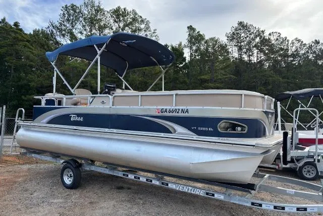 Slide: The Image of 2012 Tahoe Pontoon VT 2285 EL on trailer, blue canopy, parked outdoors. - 1