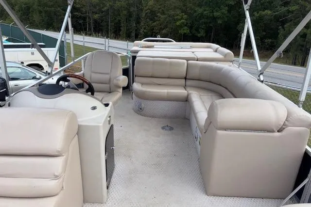 Slide: The Image of 2012 Tahoe Pontoon VT 2285 EL with spacious seating and steering console, parked near a road. - 10
