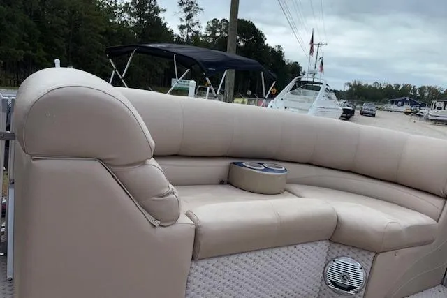Slide: The Image of 2012 Tahoe Pontoon VT 2285 EL with beige seating and cup holders, docked near other boats. - 14