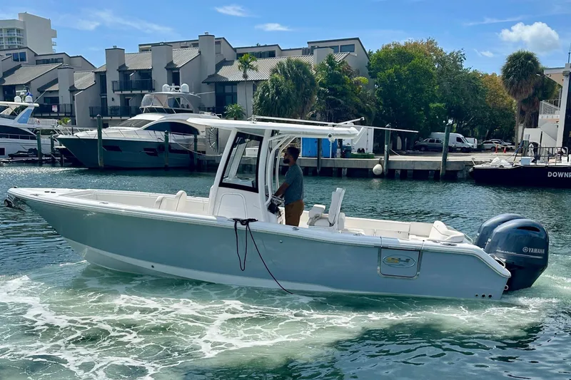 Slide: The Image of 2023 Sea Hunt Ultra 265 SE boat cruising in a marina with modern buildings. - 8