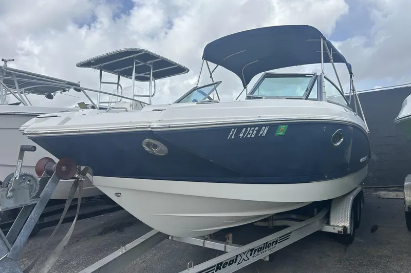 The Image of 2013 Chaparral Sunesta 224 boat on trailer, blue and white exterior, parked outdoors. - 1
