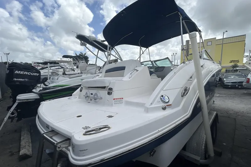 Slide: The Image of 2013 Chaparral Sunesta 224 boat with canopy, docked alongside other vessels under a cloudy sky. - 6