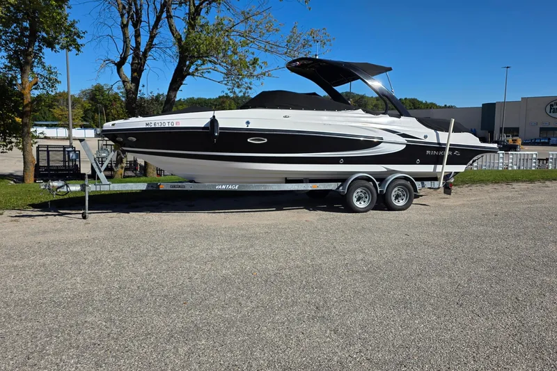 The Image of 2013 Rinker 276 Captina boat on trailer, parked outdoors under clear blue sky. - 0