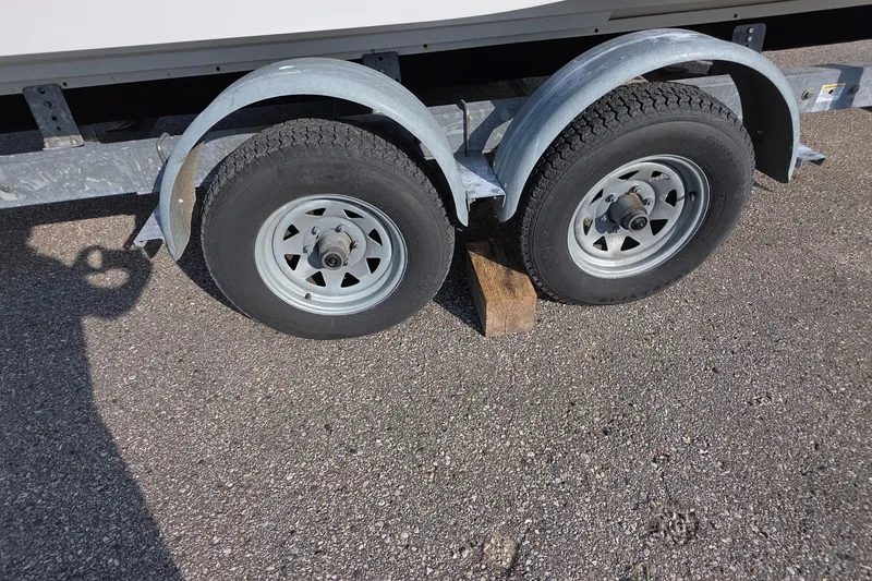 Slide: The Image of Trailer wheels of a 2013 Rinker 276 Captina boat, secured with a wooden block. - 42