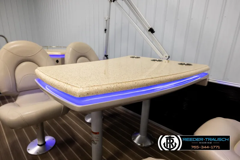 Slide: The Image of 2016 Bennington 24 SPDXDF boat interior with beige seating and illuminated table. - 24