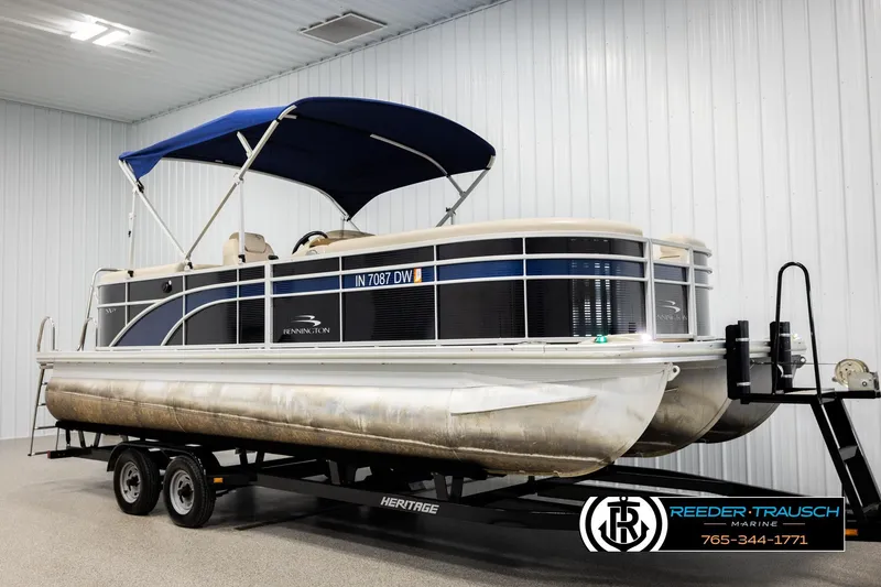 Slide: The Image of 2016 Bennington 24 SPDXDF pontoon boat with blue canopy on trailer in indoor storage. - 3