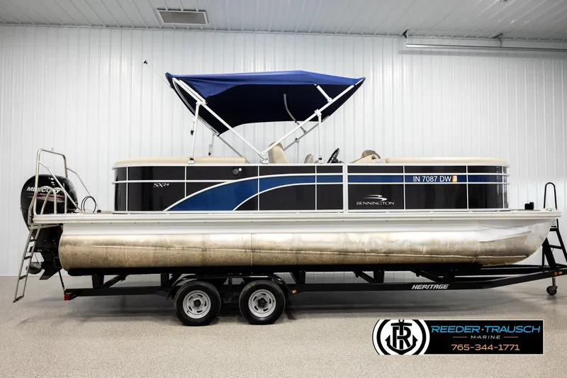 Slide: The Image of 2016 Bennington 24 SPDXDF pontoon boat with blue canopy on trailer in showroom. - 5