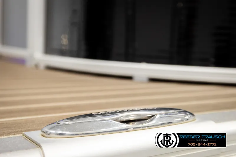 Slide: The Image of 2016 Bennington 24 SPDXDF boat cleat on wooden deck, Reeder-Trausch Marine logo visible. - 57