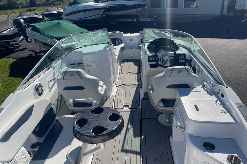 Slide: The Image of 2023 Hurricane SunDeck 2400 OB boat interior with seating, steering wheel, and table. - 4