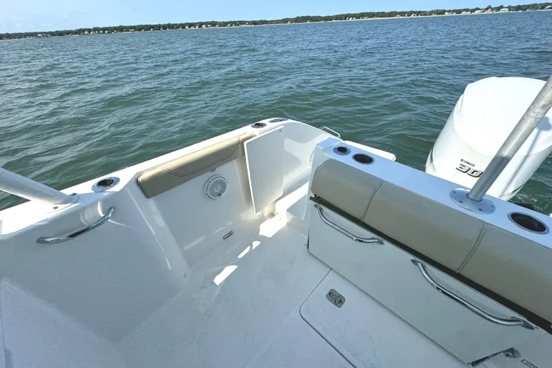 Slide: The Image of 2020 Pursuit DC 235 Dual Console boat on a serene lake with trees in the background. - 10