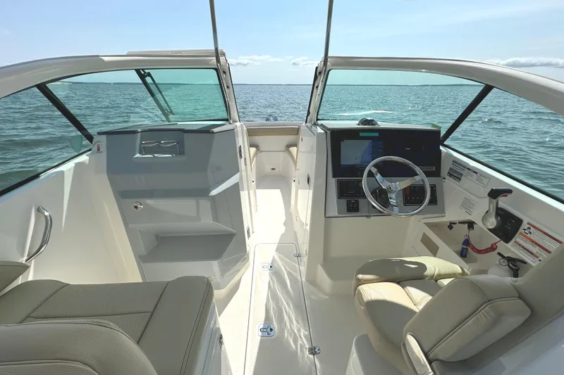 Slide: The Image of 2020 Pursuit DC 235 Dual Console boat interior with beige seating and wood-like flooring. - 17