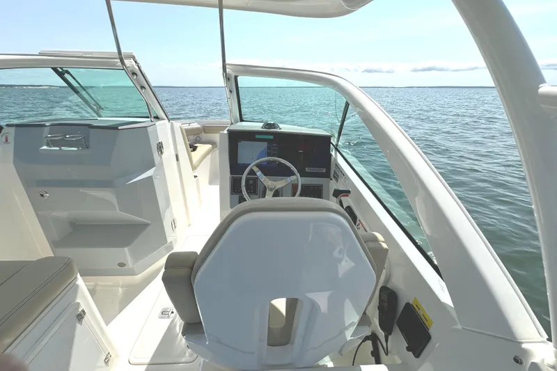 Slide: The Image of 2020 Pursuit DC 235 Dual Console boat interior with beige seating and wood-style flooring. - 18