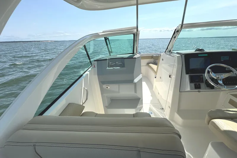 Slide: The Image of 2020 Pursuit DC 235 Dual Console boat interior with beige seating and ocean view. - 24