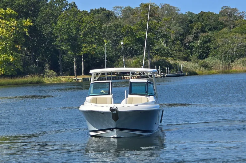 Slide: The Image of 2020 Pursuit DC 235 Dual Console boat on calm water near shoreline homes. - 5