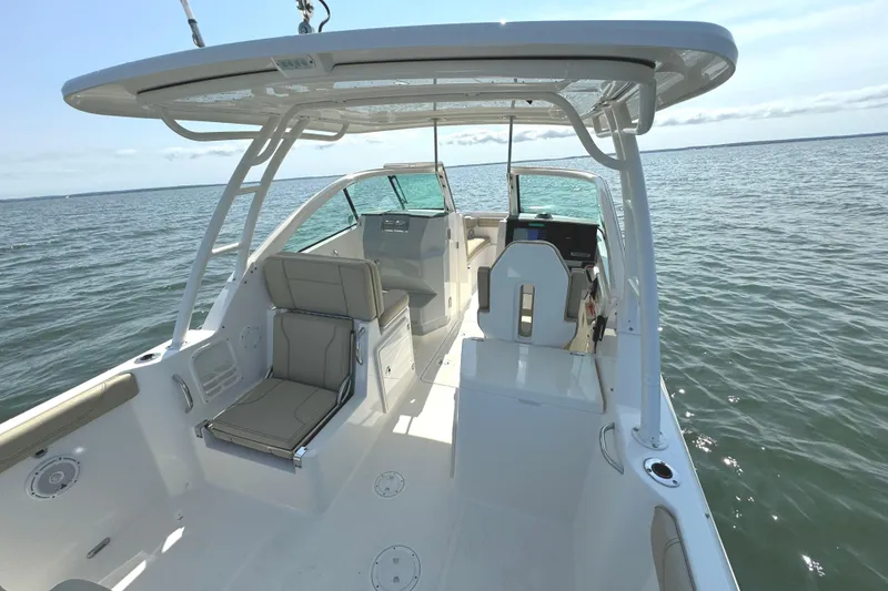 Slide: The Image of 2020 Pursuit DC 235 Dual Console boat on calm water, surrounded by trees and houses. - 6