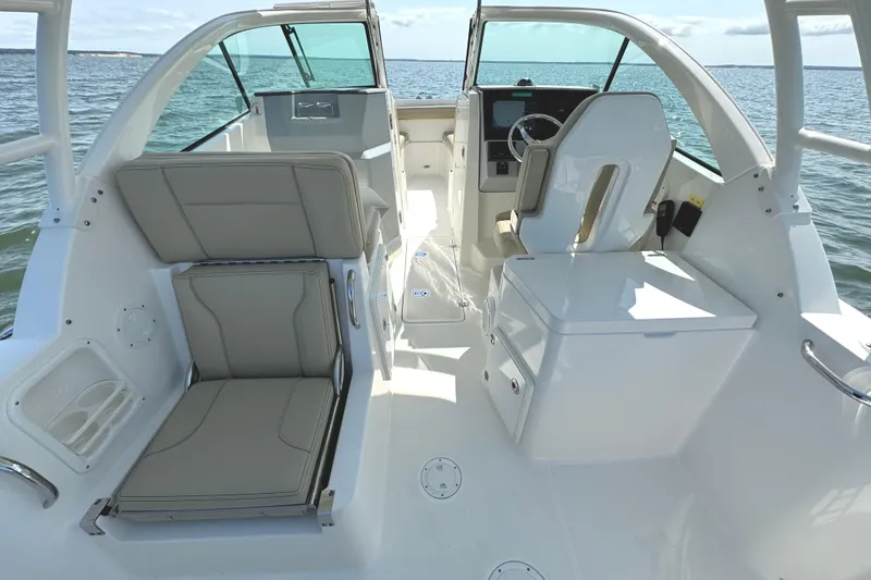 Slide: The Image of 2020 Pursuit DC 235 Dual Console boat on a serene lake with trees in the background. - 9