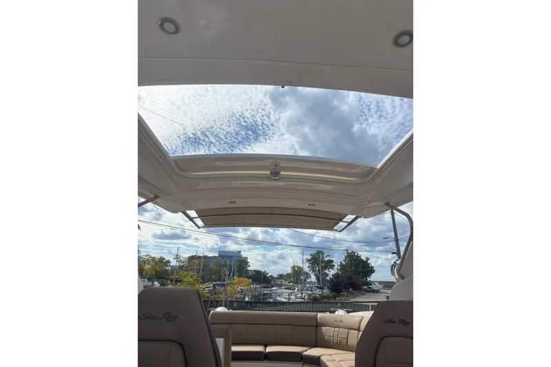 Slide: The Image of 2016 Sea Ray 350 SLX boat interior with open sunroof, showcasing sky and marina view. - 17