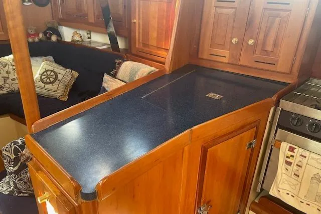 Slide: The Image of Interior of a 2001 Tartan 3700 sailboat with wooden cabinetry and blue countertop. - 10