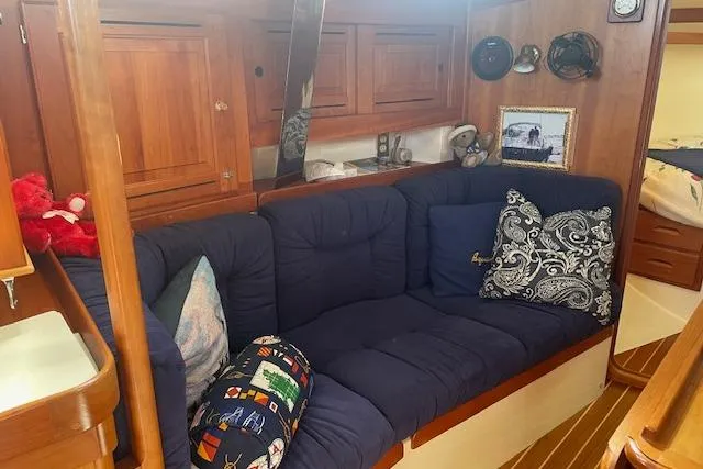 Slide: The Image of Cozy interior of 2001 Tartan 3700 sailboat with blue cushions and wooden cabinetry. - 3