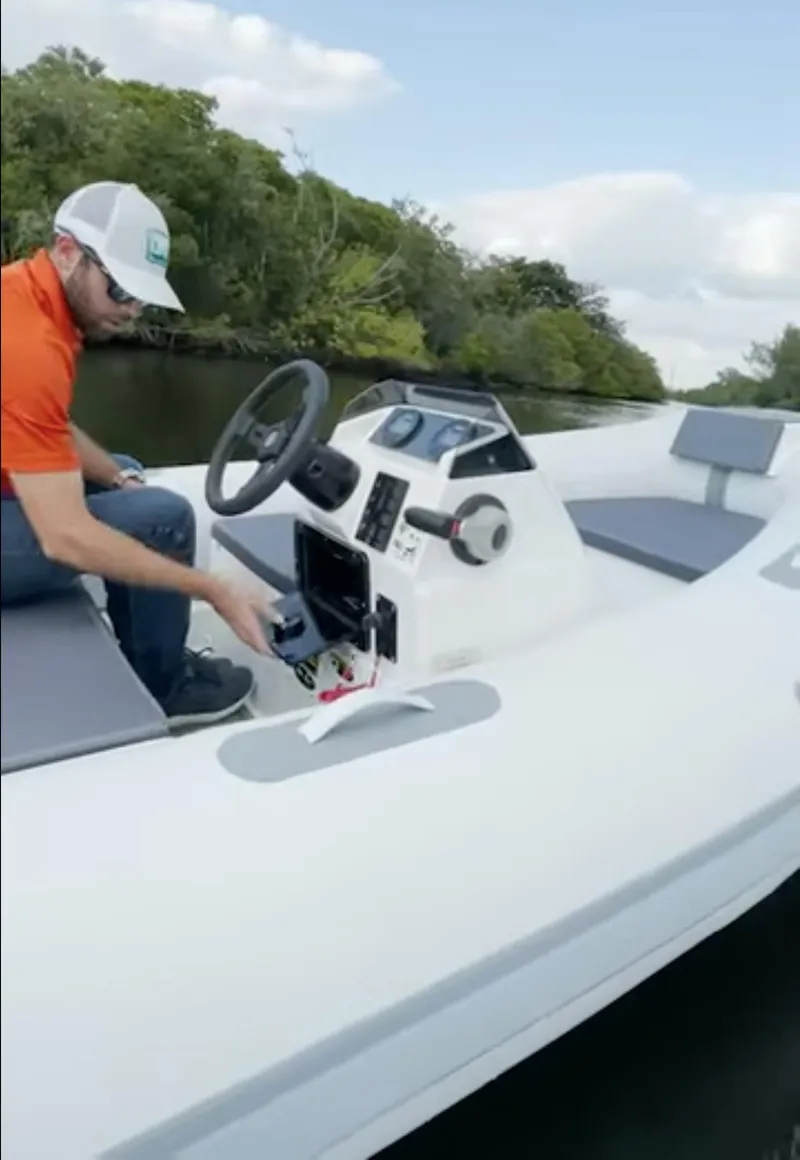 Slide: The Image of 2023 Northstar Axis 3.8 boat on water, man adjusting controls, lush greenery background. - 5