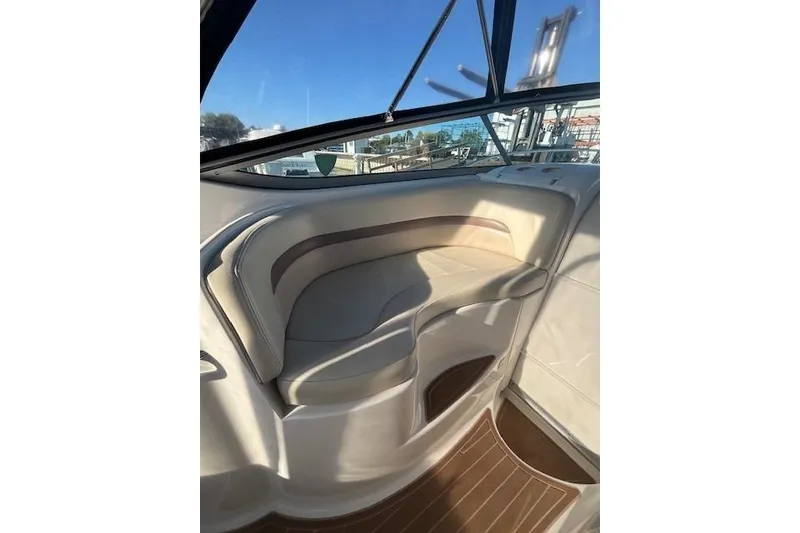 Slide: The Image of Interior seating of 2005 Chaparral 290 Signature boat, featuring beige upholstery and window view. - 15