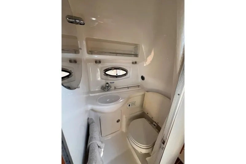 Slide: The Image of 2005 Chaparral 290 Signature boat bathroom with sink, toilet, and porthole window. - 23