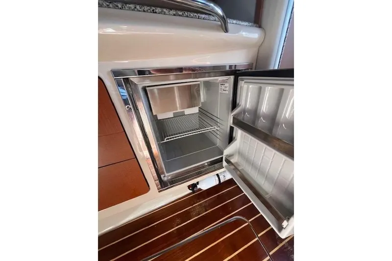 Slide: The Image of Open refrigerator inside 2005 Chaparral 290 Signature boat, featuring wooden flooring. - 25