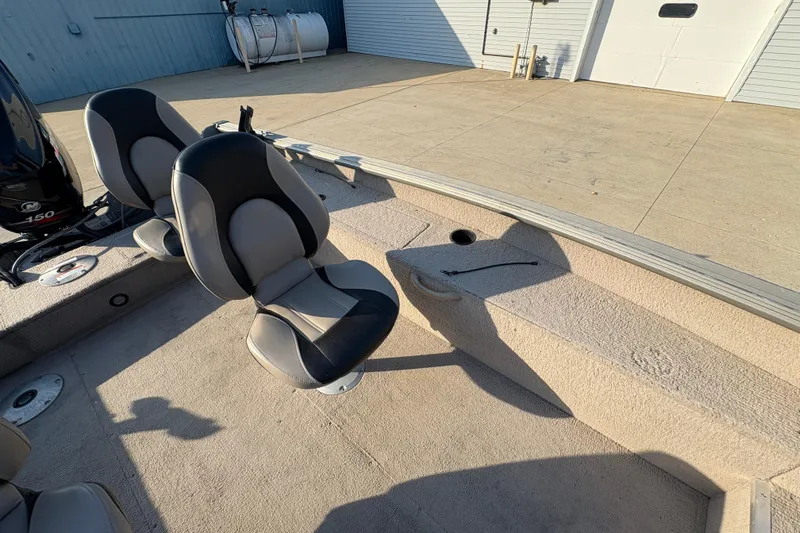 Slide: The Image of 2004 Lund 1800 Explorer SS boat interior with two seats and motor, parked on concrete. - 21